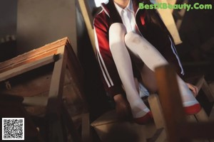 A woman in a school uniform standing on a pile of wooden chairs.