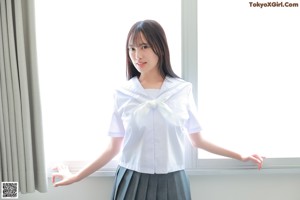 A woman in a school uniform is sitting on the floor.