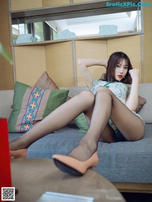 A woman in a blue dress sitting on a couch.