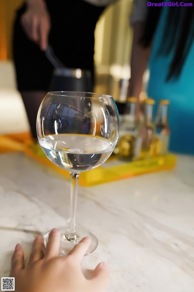 A person holding a glass of white wine on a table.