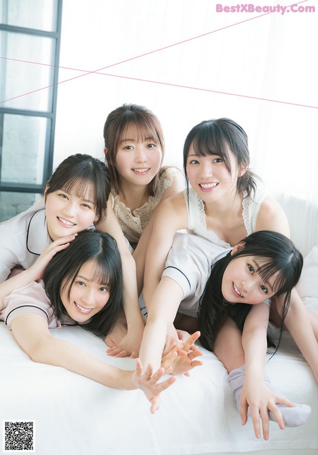 A group of young women laying on top of a bed.