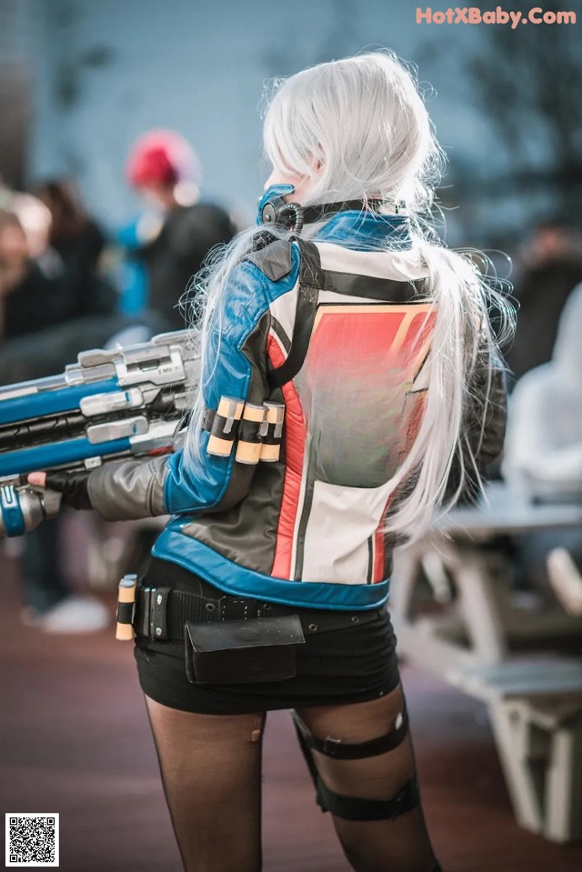 A woman in a leather jacket holding a gun.